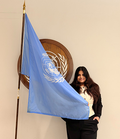 Sanaaya Joisher with the UN flag at ECOSOC Youth Forum 2026